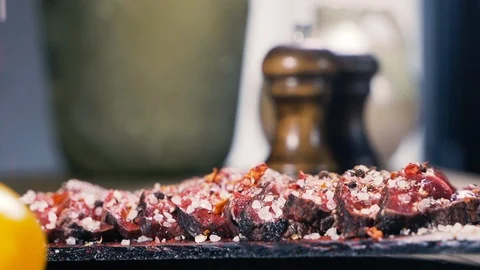 Adds salt and pepper to the dish, salt falling in slow motion 스톡 동영상 107740247