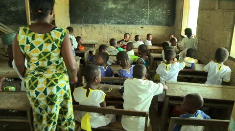 ADEISO CLASSROOM TEACHER MOVES TO FRONT OF CLASS AND SEATS TWO CHILDREN Stock Footage 58066589