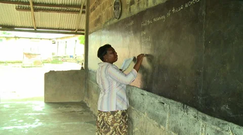ADEISO CLASSROOM TEACHER WRITES ON BLACKBOARD PAN TO STUDENTS Stock Footage 57982703