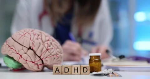 ADHD abbreviation with brain model and pills on woman doctor desk Stock Footage 313290806