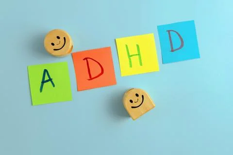 ADHD abbreviation on multi-colored paper and two wooden smileys. Stock Photos