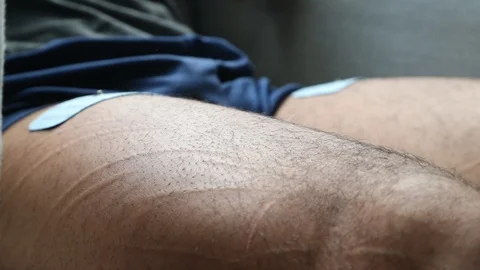 Adhesive pads are applied to male bodybuilder's legs in slow motion Stock Footage 88642753