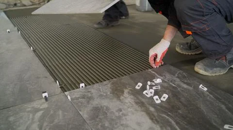 Adhesive solution for gluing ceramic floor tiles. Professional worker gluing Stock Photos