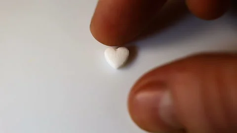 Adjust a small white pill in the form of a heart on a white background. Get your Stock Footage 145374620