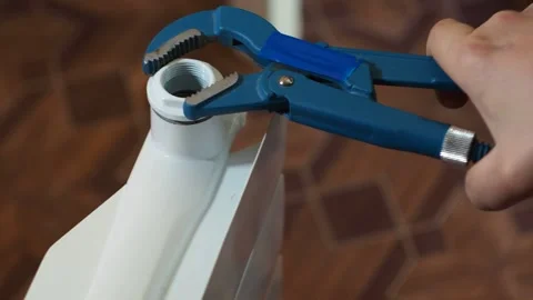 Adjustable blue key tighten the coupling on the radiator. installation of the Stock Footage 143273848