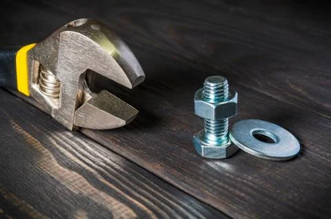 Adjustable spanner with metal nut and bolt on black vintage wooden background Stock Photos