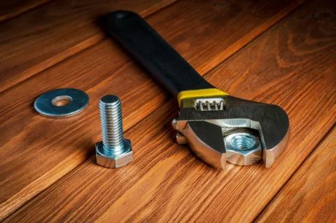 Adjustable spanner with metal nut and bolt on vintage wooden background Stock Photos