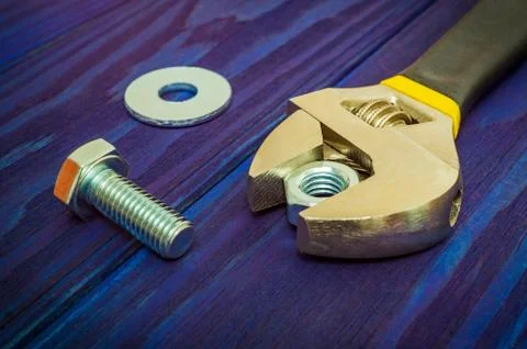 Adjustable spanner with metal nut and bolt on blue vintage wooden background Stock Photos