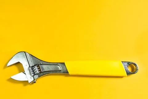 Adjustable universal spanner wrench on yellow background. Construction and .. Stock Photos