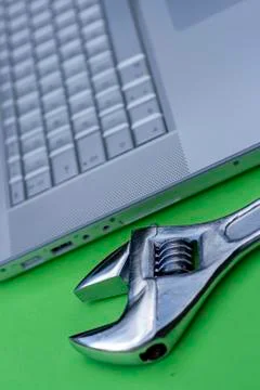 Adjustable wrench next to a silver laptop. Computer service, maintenance them Stock Photos
