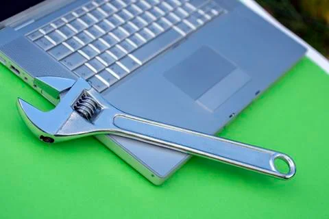 Adjustable wrench next to a silver laptop. Computer service, maintenance them Foto stock