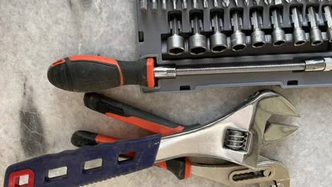 Adjustable wrench, plier, and screwdriver bit set on a stone surface Stock-Footage 328506365
