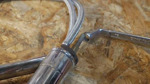 Adjustable wrench turning hex nut on braided metal hose fitting Stock Footage 342867173
