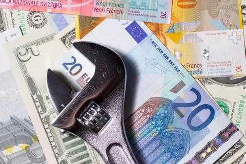 Adjustable wrench on various Euro, US dollar and Swiss franc banknotes Stock Photos