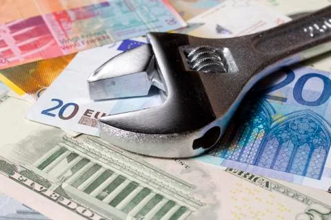 Adjustable wrench on various Euro, US dollar and Swiss franc banknotes Stock Photos