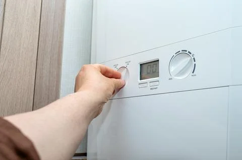 Adjusting boiler temperature setting. Concept of heating, energy usage, and Stock Photos