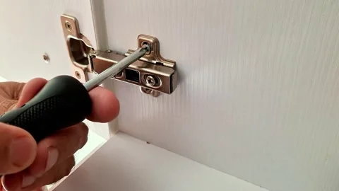 Adjusting a Cabinet Door Hinge with a Screwdriver for Proper Alignment and Fit Vidéo 346802535