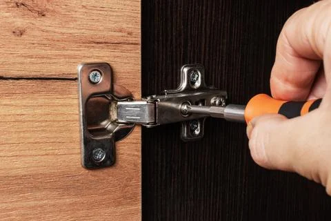 Adjusting the door hinge of a room cupboard Stock Photos