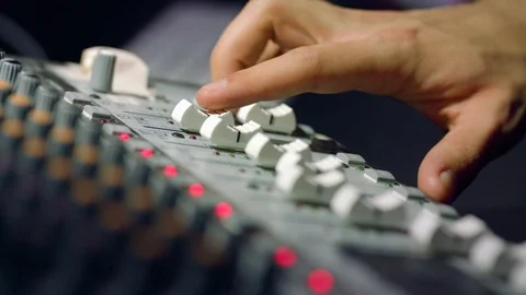 Adjusting faders on 16 track audio mixer board at voiceover session Stock Footage 86534554
