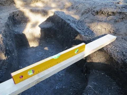 Adjusting horizontal plane with a bubble level of a dug stepped hole Stock Photos