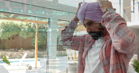Adjusting man in pink plaid securing turban, viewing code on glass door at home, Stock Photos