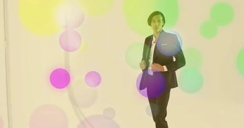 Adjusting model wearing black suit jacket, pants in studio with colored circles Stock Photos