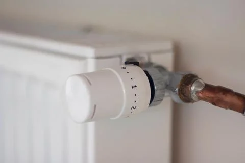 Adjusting radiator temperature using thermostat in apartment Stock Photos