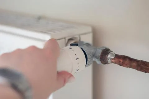Adjusting the radiator temperature using a thermostat in an apartment Stock Photos