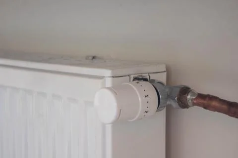 Adjusting the radiator temperature using a thermostat in an apartment Stock Photos