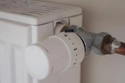Adjusting the radiator temperature using a thermostat in an apartment Stock Photos