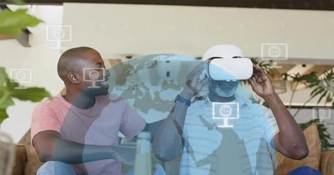 Adjusting senior man in light blue polo fitting white VR headset on beige sofa, Stock Photos