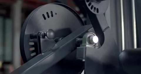 Adjusting the settings of a gym leg machine for targeted muscle training. Stock Footage 316486056