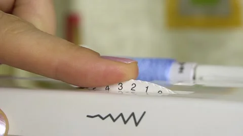 Adjusting the stitch width adjuster in the sewing machine. Stockbeeldmateriaal 140052731