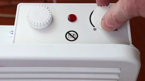 Adjusting thermostat of convector heater to control temperature by turning dial. Video stock 235790892