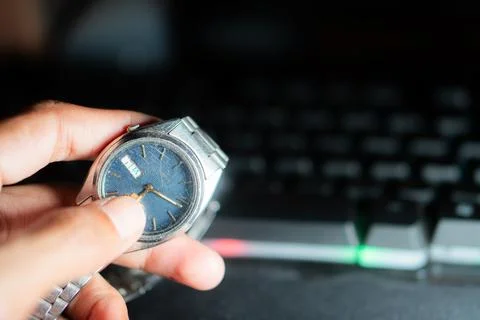 Adjusting wristwatch time in front of computer keyboard Stock Photos