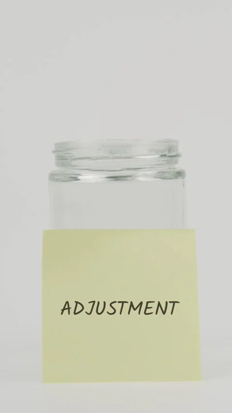 Adjustment text or word on yellow sticky note attached to glass jar with han Stock Footage 311675505
