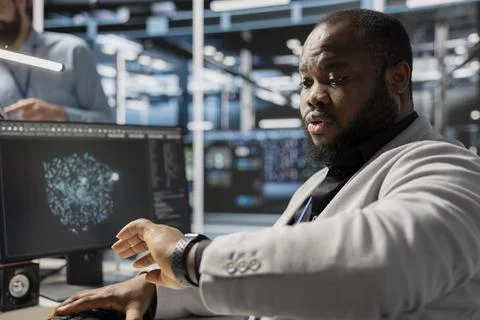 Admin in data center checking time during late shift while working on PC Stock Photos