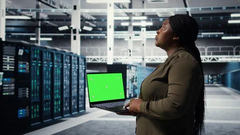 Admin in data center uses green screen laptop to ensure error free networks Stock Photos