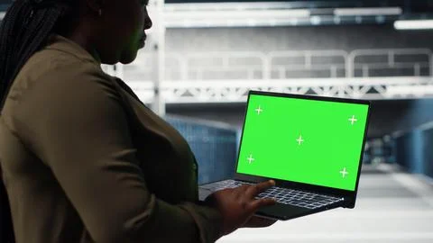 Admin in data center uses green screen laptop to ensure error free networks Stock Photos