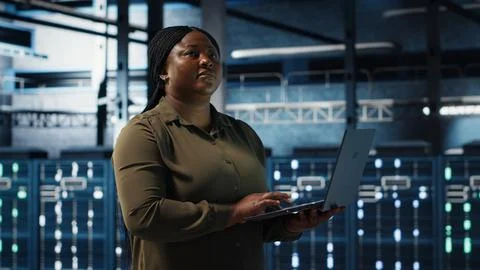 Admin in data center using app on laptop to ensure error free rigs networks Stock Photos