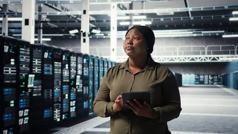 Admin walking in data center, using tablet to manage software updates Stock Photos