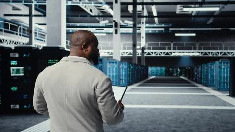 Admin walking in high tech data center facility, checking equipment Stockfoto's