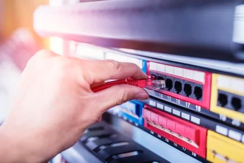 Administrator holding network cables connected to servers Stock Photos