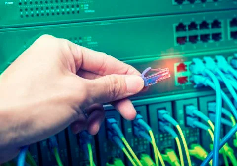 Administrator holding network cables connected to servers Stock Photos