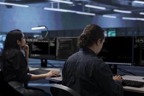 Admins in data center typing on computers, fixing errors Stock Photos
