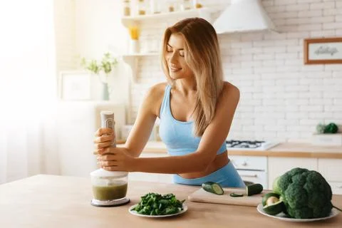 Admirable lady preparing a vegetable smoothie in her kitchen Stock Photos