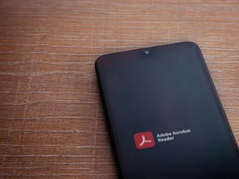 Adobe Acrobat Reader app launch screen with logo on the display of a black mo Stock Photos