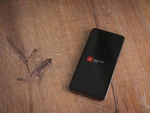 Adobe Acrobat Reader app launch screen with logo on the display of a black mo Stock Photos