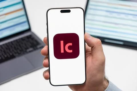 Adobe LC logo on the screen of smartphone in mans hand on the workplace Stock Photos