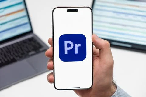 Adobe Premiere Pro CC logo on the screen of smartphone in mans hand on the Stock Photos
